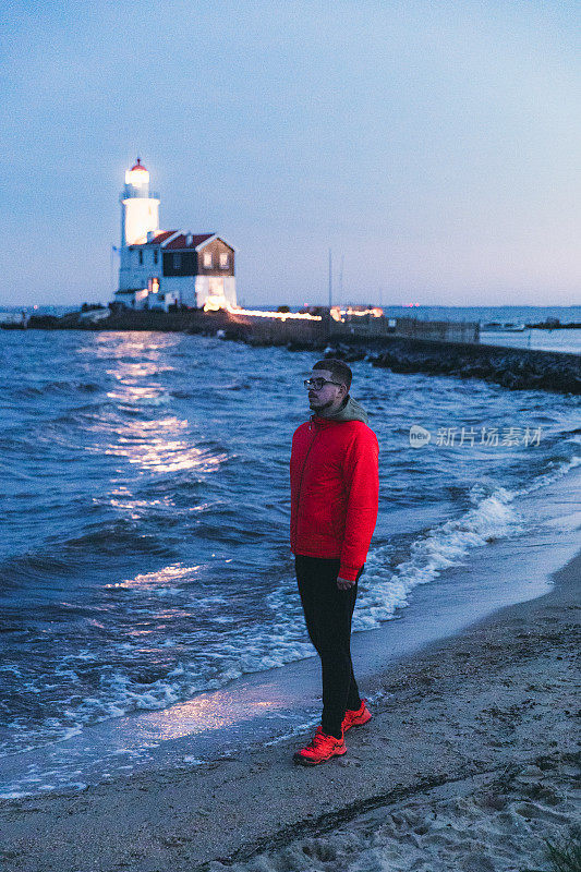 在荷兰，一个人在美丽的灯塔附近的海滩上散步，欣赏星空