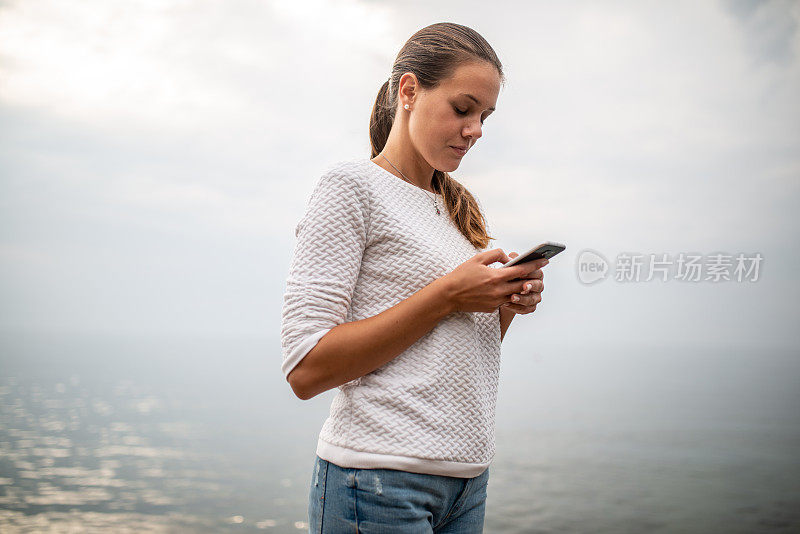 一名年轻女子在雾天户外使用手机