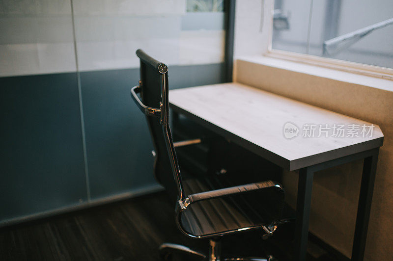 一间办公室内部，窗户旁边有办公椅和桌子