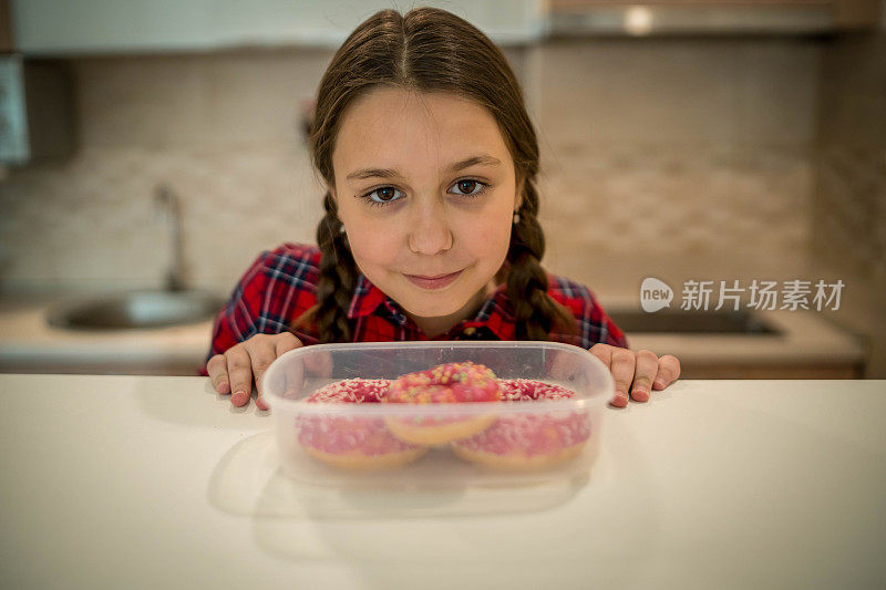 对孩子的饮食。悲伤和不快乐的孩子触及甜甜圈。孩子们的美味食物。孩子在看甜甜圈。垃圾食品上瘾。