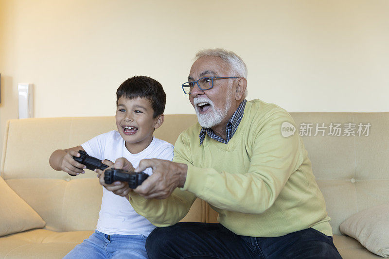 心不老的爷爷正在和他的小孙子玩电子游戏。