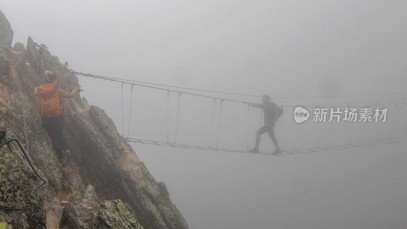 登山运动员从山上爬上吊桥