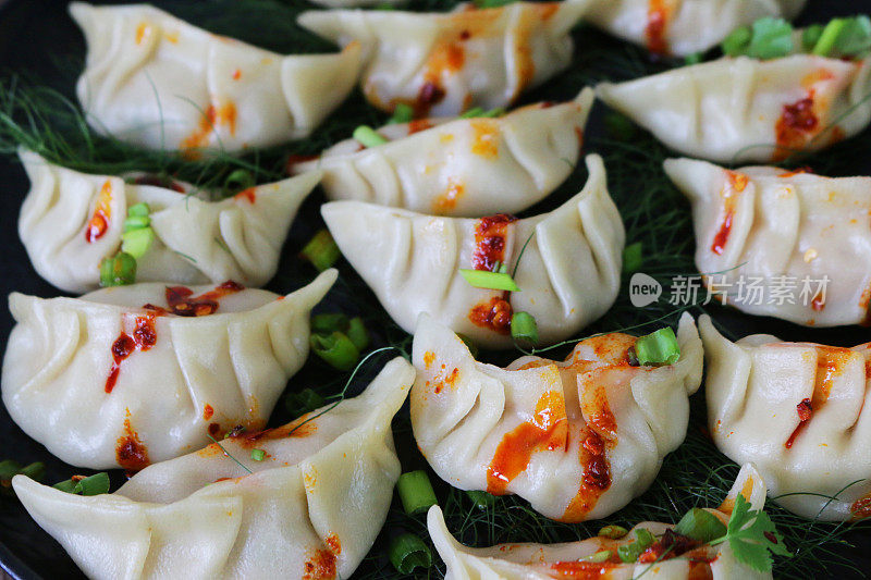 整个画面是蒸饺(南亚饺子)，白面粉和水面团里填满了鸡肉和混合蔬菜，淋上辣椒油，再铺上茴香，再配上葱花和香菜叶，这是一幅俯瞰美景的画面