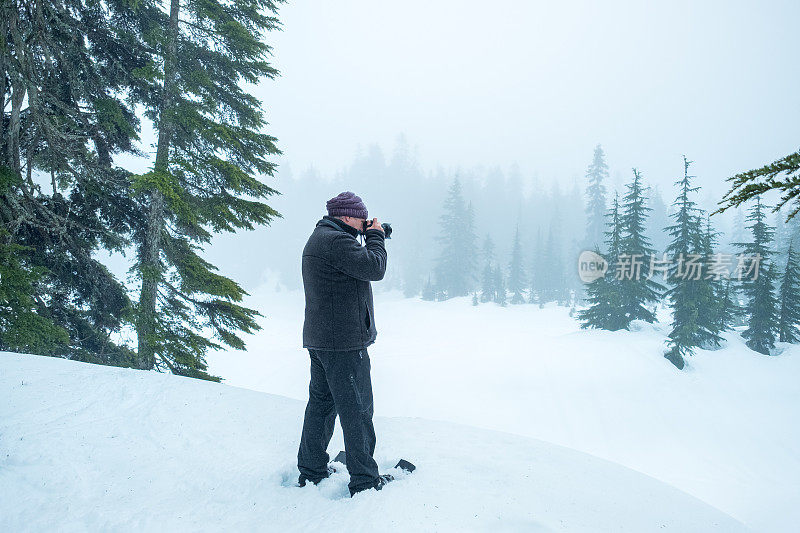 成熟的男人在雪鞋上拍照的迷雾森林