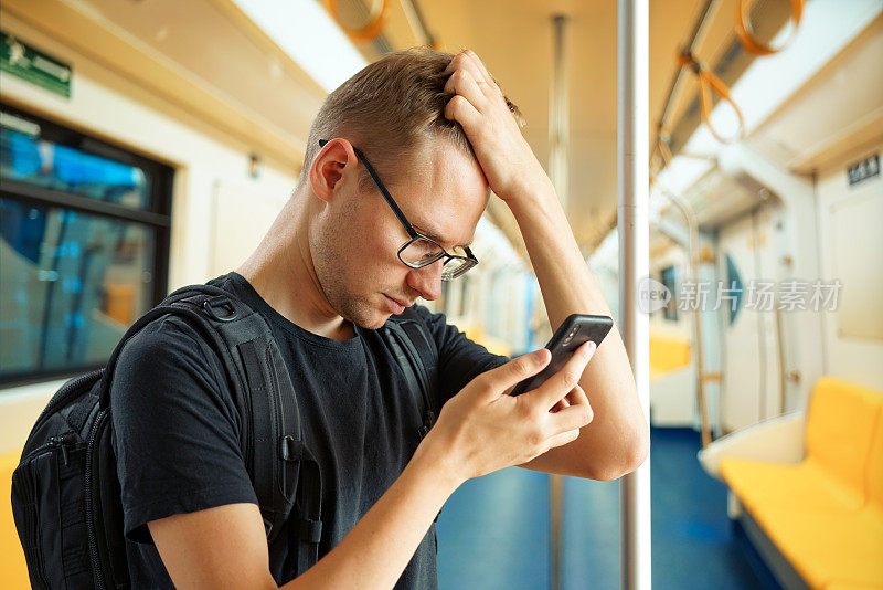 一名男子在空地铁车厢里用手机打字