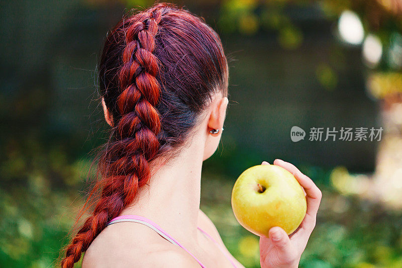 梳着辫子的年轻女子正在吃苹果