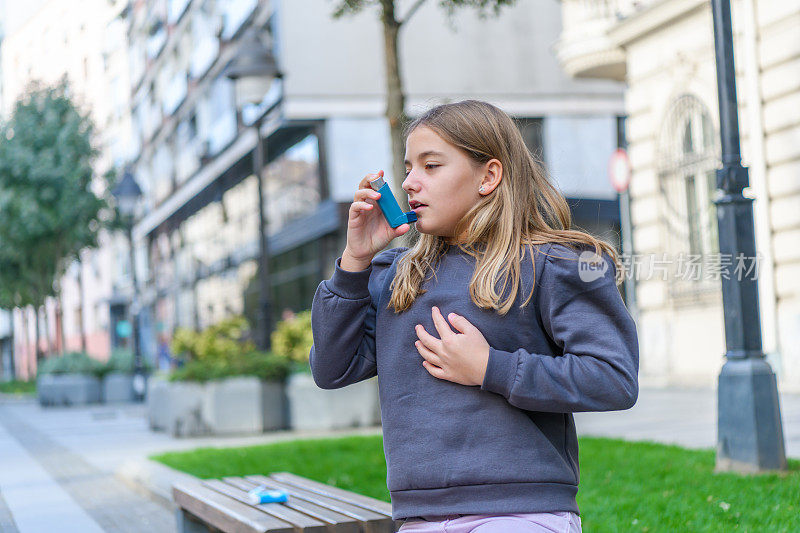 哮喘小女孩在公园里使用吸入器。