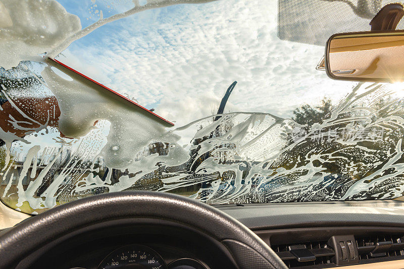 那个人正在用橡皮擦擦汽车的玻璃窗户。