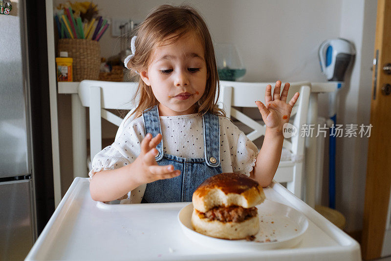 小女孩在厨房里吃汉堡包