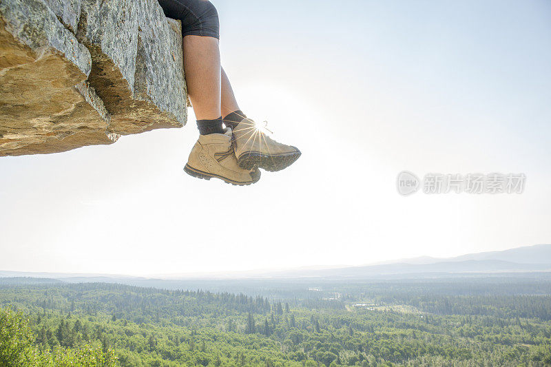 登山者的双脚从山顶垂下来，绳索靠在旁边