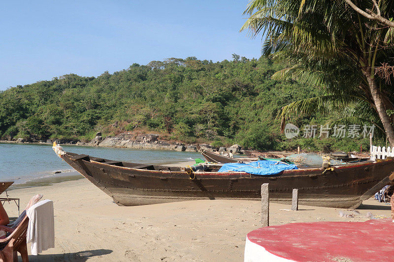 印度果阿海滩，木制渔船停泊在棕榈树旁的海滩上