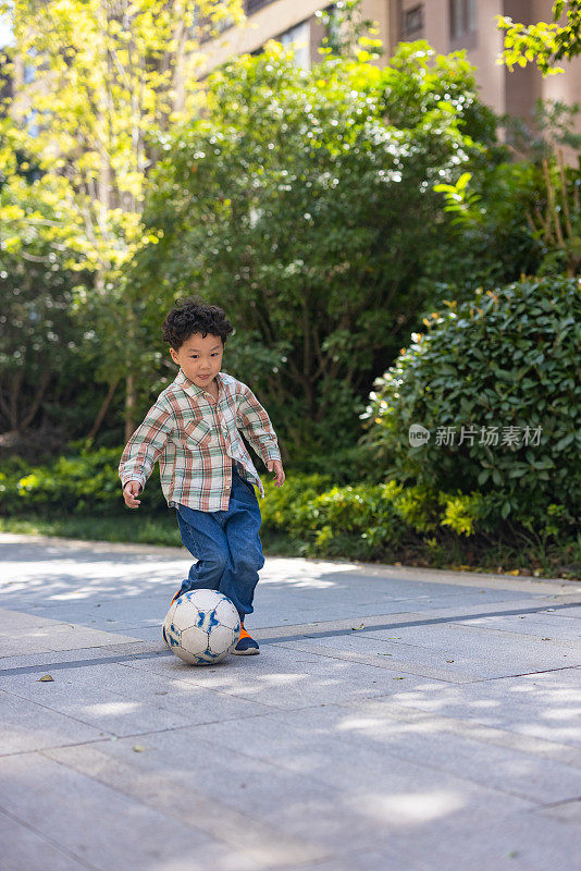 一个小男孩在院子里踢足球