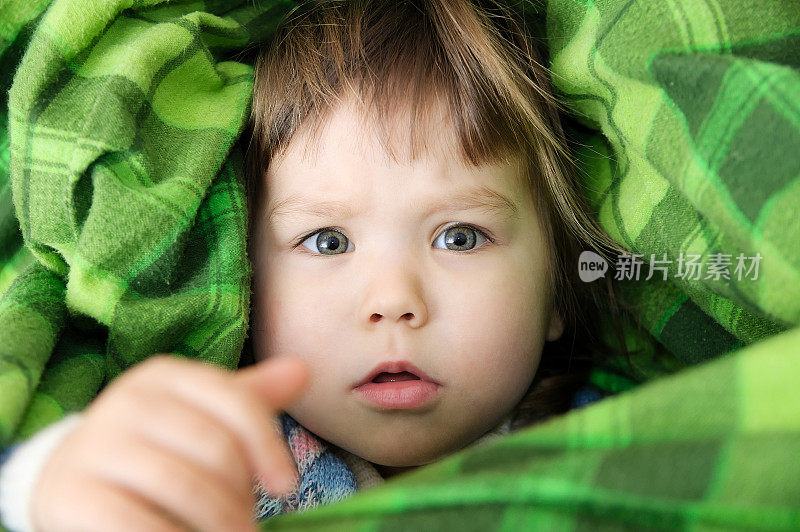 孩子肖像在毯子拉手