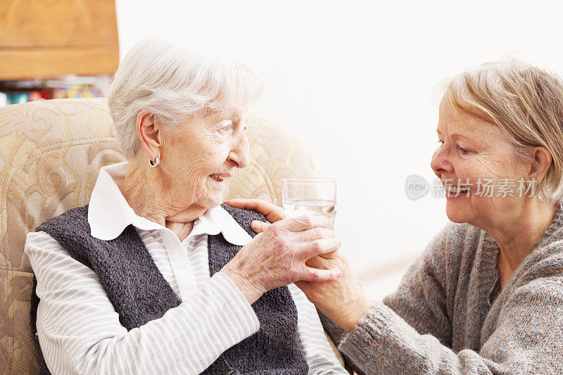 年长的妇女从善良成熟的看护人那里取水