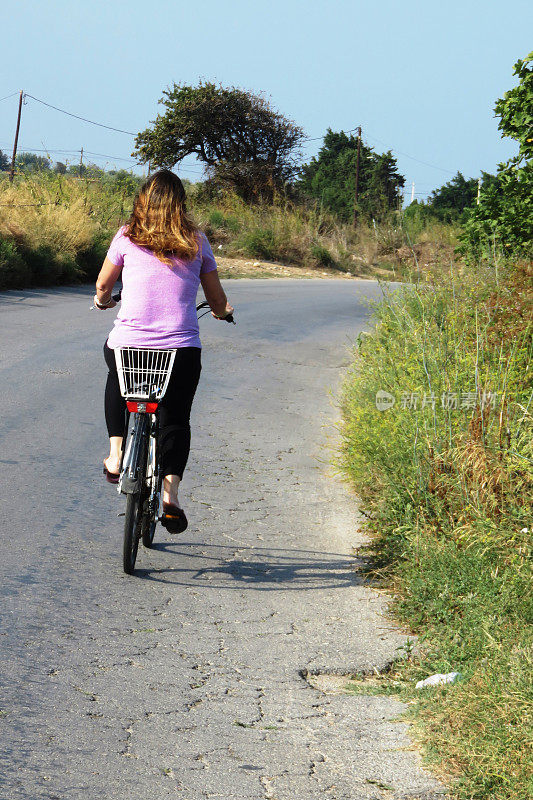 女孩骑着自行车在乡村公路上