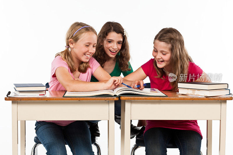 三个女孩在学校的课桌前工作。