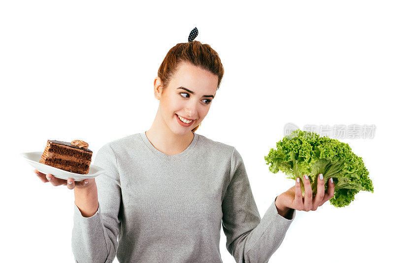 健康饮食的女人拿着生菜和甜巧克力蛋糕