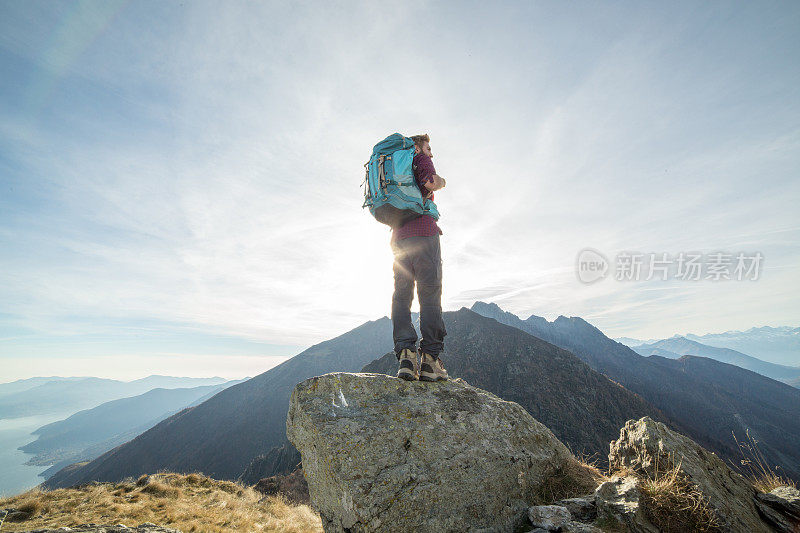 一个年轻的徒步旅行者站在山顶上