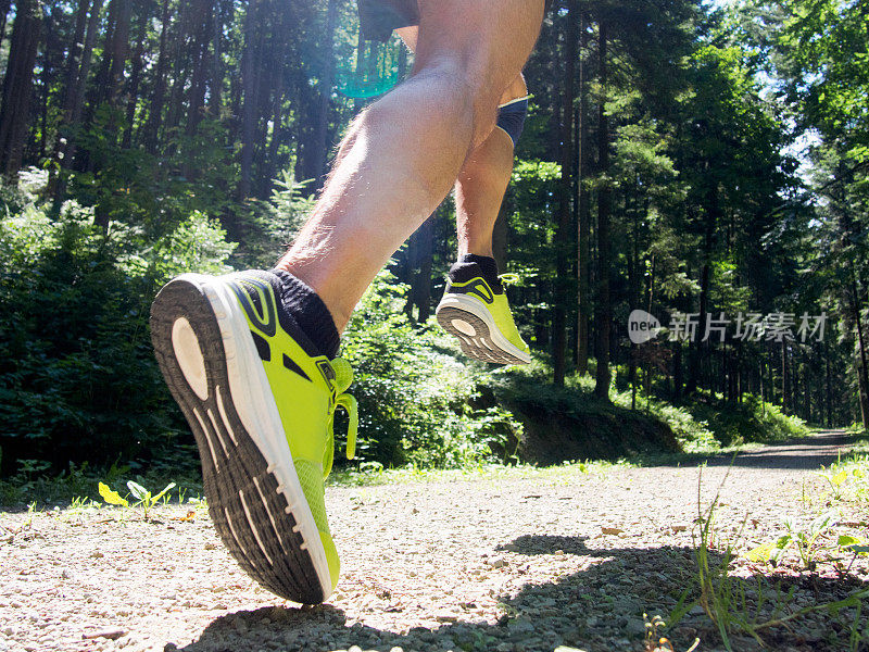 男跑步者在路上穿过森林。关注的腿。
