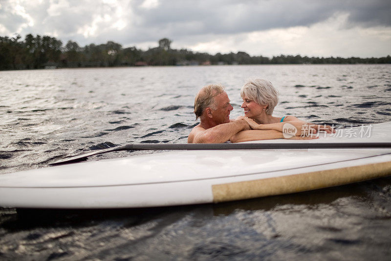 浪漫的老年夫妇与桨板在海上