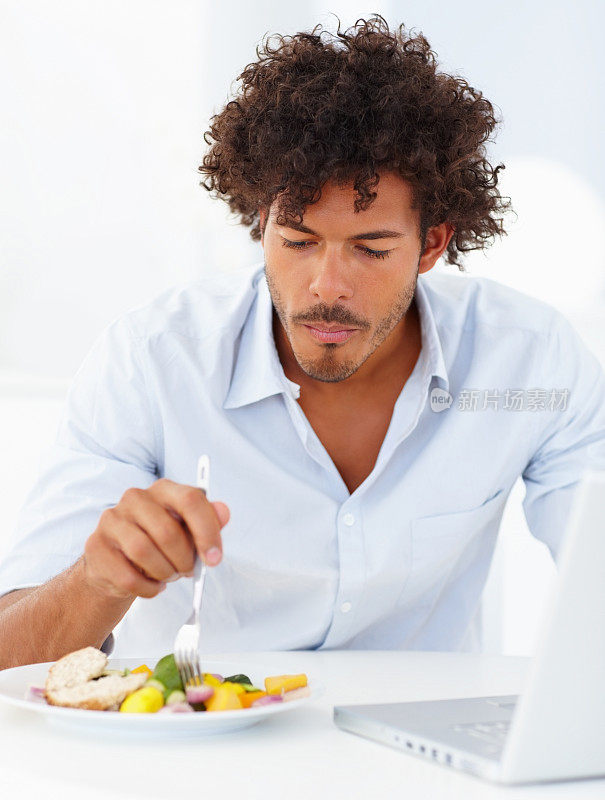快乐的年轻人一边吃饭一边玩笔记本电脑