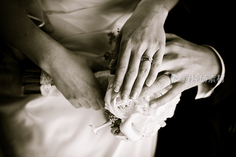 新郎和新娘手牵手越过玫瑰花束和戒指