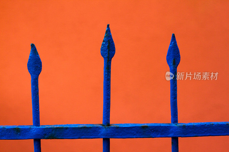 尖顶钴蓝色栅栏对抗火焰橙色墙