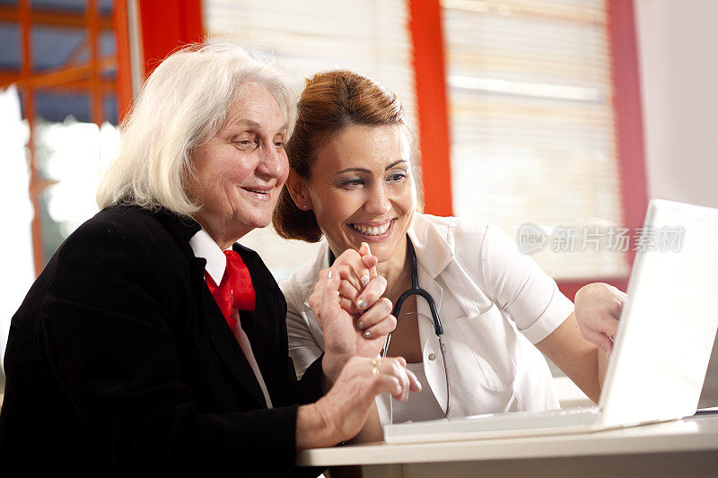 医生或护士与年长妇女用电脑交谈