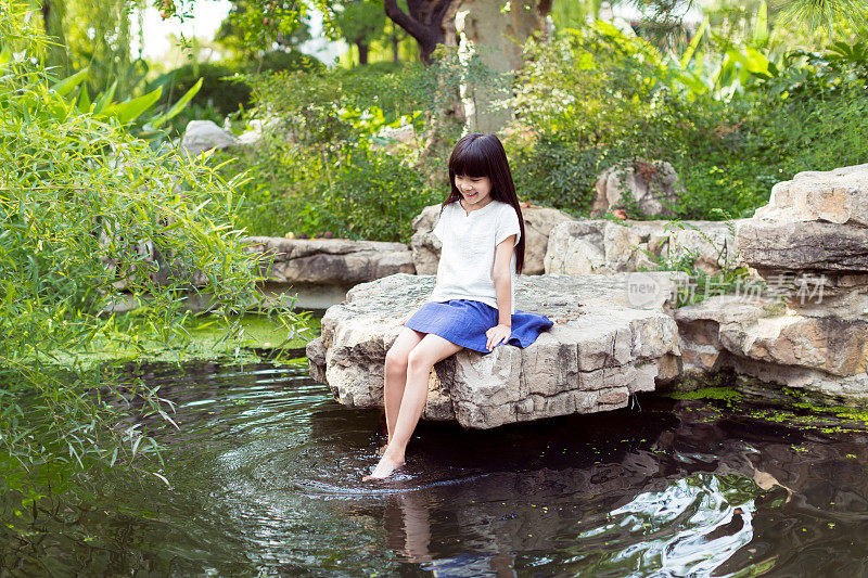漂亮的小女孩在池塘里玩
