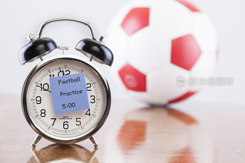运动时间:闹钟与足球练习提醒。球的背景。