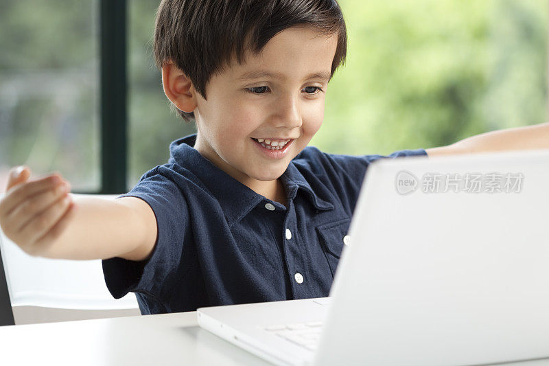 一个学龄前的男孩在用白色的笔记本电脑