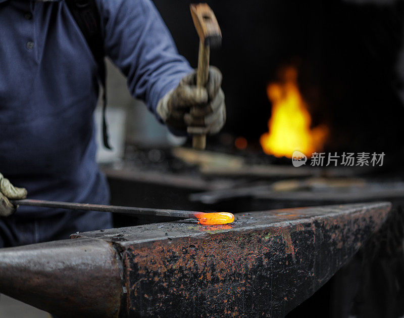 铁匠用铁锤在铁砧上敲打金属