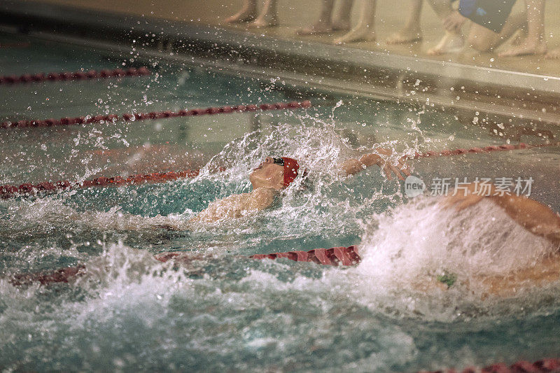 十几岁的男孩在高中游泳比赛中游仰泳