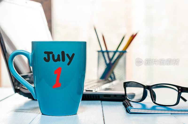 7月1日。月1日，彩色日历上的早上咖啡杯在商务工作场所背景。夏天的概念。文本空白