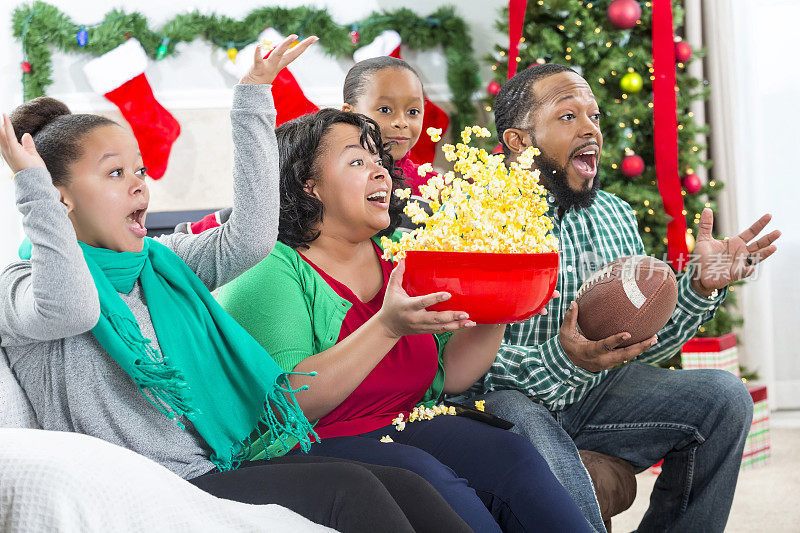 激动的非裔美国人家庭在电视上观看足球比赛