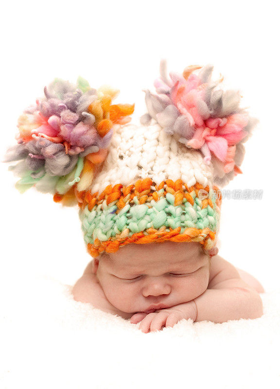 刚出生的婴儿戴着可笑的彩色帽子睡着了