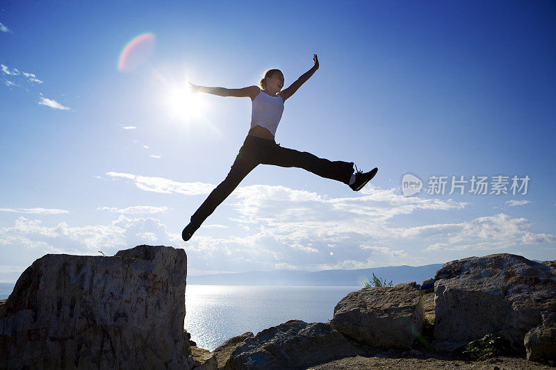 穿着白色背心的女人从一块石头跳到另一块石头