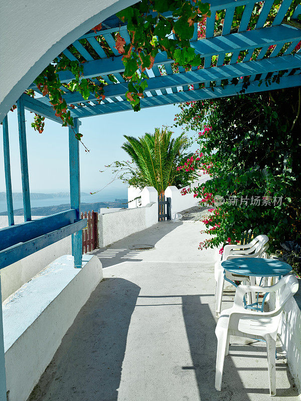 两张椅子和一张小桌子，在美丽的露台上可以看到希腊圣托里尼的美丽海景