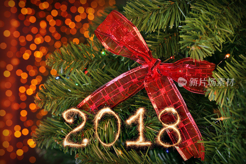 2018年的新年标志用闪闪发光的痕迹在圣诞树上