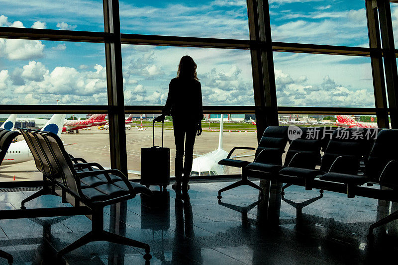 那个女人的剪影，那个旅客拿着行李站在机场
