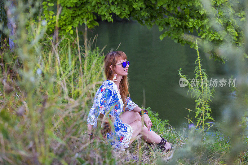 戴墨镜的女人坐在河边欣赏风景