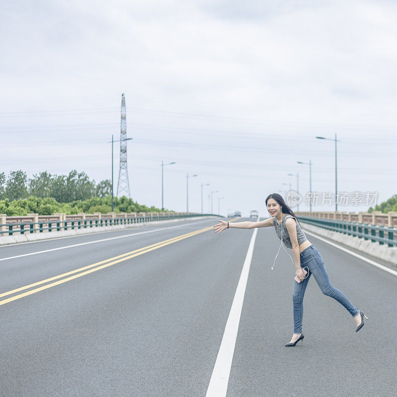 手持智能手机的女子在城市道路上招呼汽车