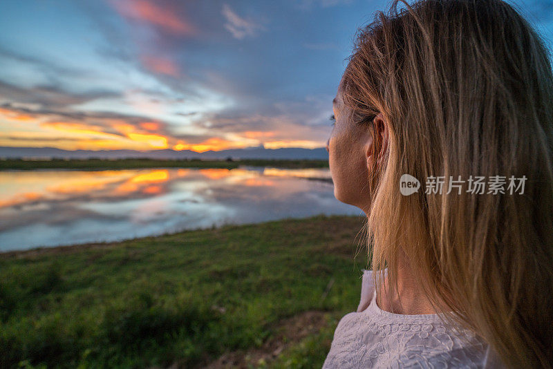 年轻女子在缅甸的湖岸凝望夕阳