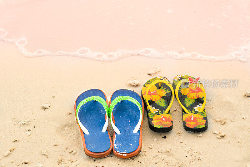 2双拖鞋在白色沙滩上，旅行和度假的时间