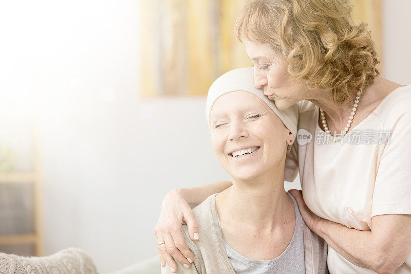 女人亲吻癌症幸存者的太阳穴