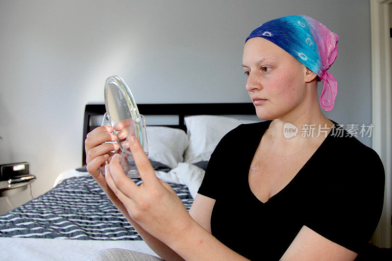 年轻的癌症患者在镜子里看着自己