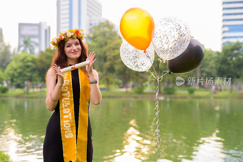 年轻美丽的女子庆祝毕业的肖像在泰国曼谷伦皮尼公园