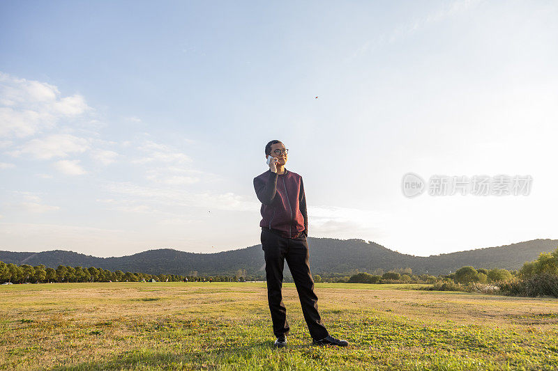 年轻的亚洲人在草地上打电话