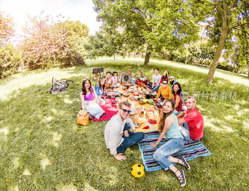 一群快乐的朋友在公共公园户外野餐-年轻人喝葡萄酒和在自然中欢笑-主要集中在底部的家伙-青春和友谊的概念-鱼眼镜头扭曲