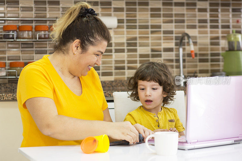 爱玩的妈妈和她的儿子在厨房使用数字平板电脑